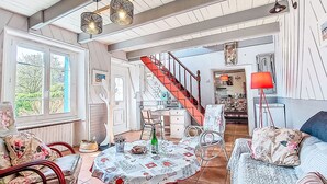 A spacious living area with a dining table, chairs, a sofa, a staircase, and a kitchen in the background. - La Chapelle by Interhome (Tréguier)