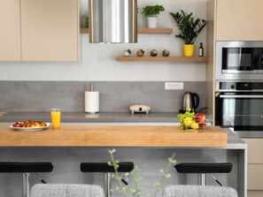 A modern kitchen with a wooden island, bar stools, a coffee machine, and a built-in oven. - Vacation home Lapis by Interhome (Poreč/Sv. Lovreč)