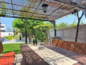 An outdoor patio with a wooden table, chairs, a pergola, and a wall-mounted grill. - Villa Roza by Interhome (Umag)