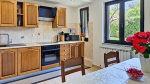 Eine Küche mit Holzausstattung, einem Backofen, einer Mikrowelle und einem Fenster mit Blick ins Grüne.