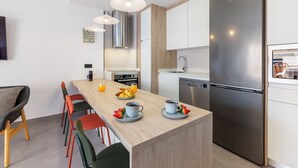 Une cuisine moderne dotée d’un îlot central, d’appareils électroménagers en acier inoxydable et d’un coin repas avec des chaises.