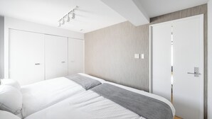 A modern bedroom with a large bed, a wardrobe, and a door. - ANAX NORD 502 (Sapporo)