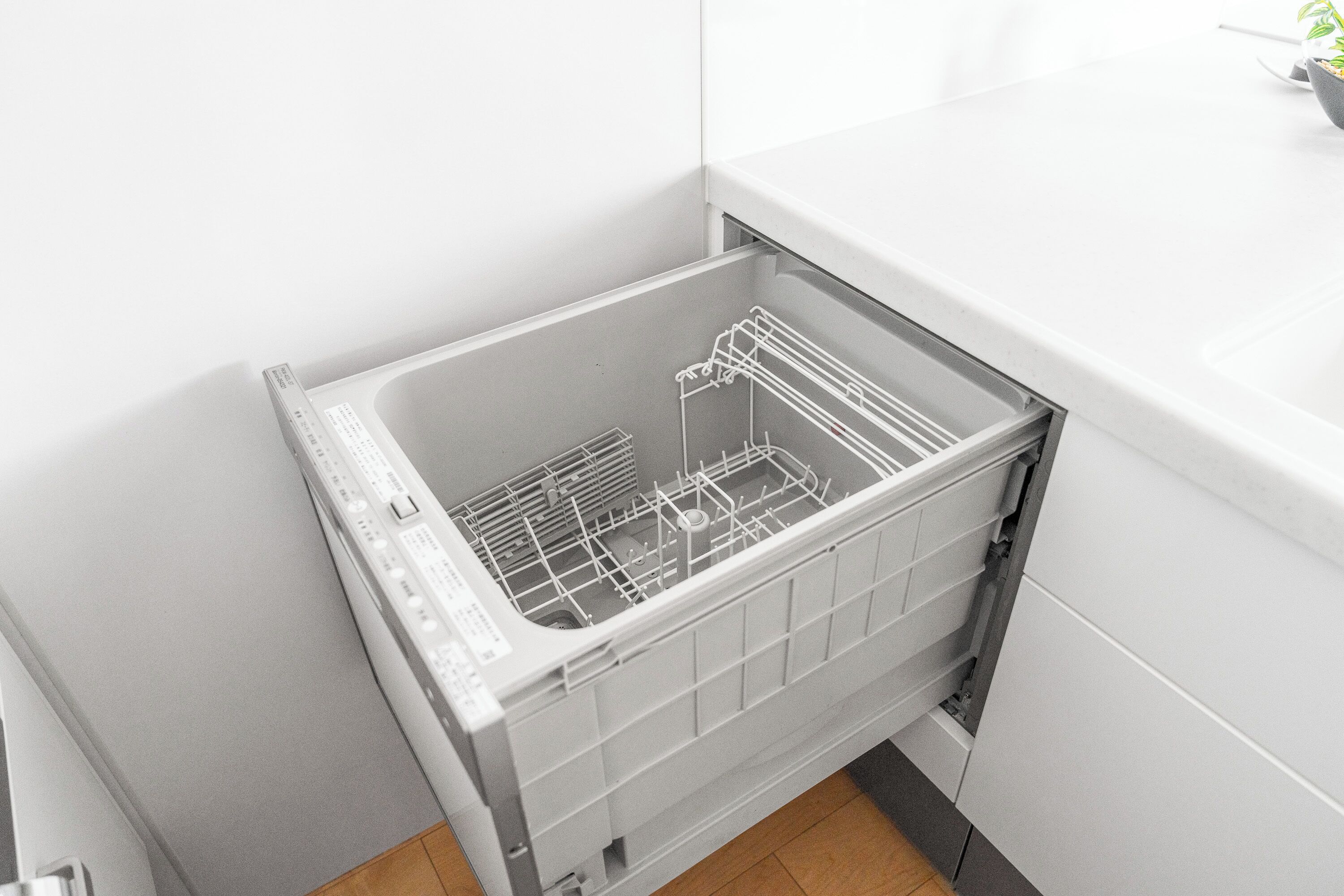 A dishwasher in a kitchen with white cabinets and a tiled floor.