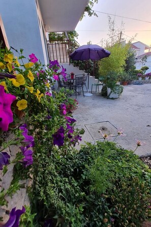 Ein möblierter Außenbereich mit Tisch und Stühlen, umgeben von Kübelpflanzen und Blumen.
