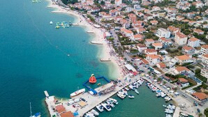 Vista aérea de un pueblo costero con puerto deportivo, playa y edificios residenciales.