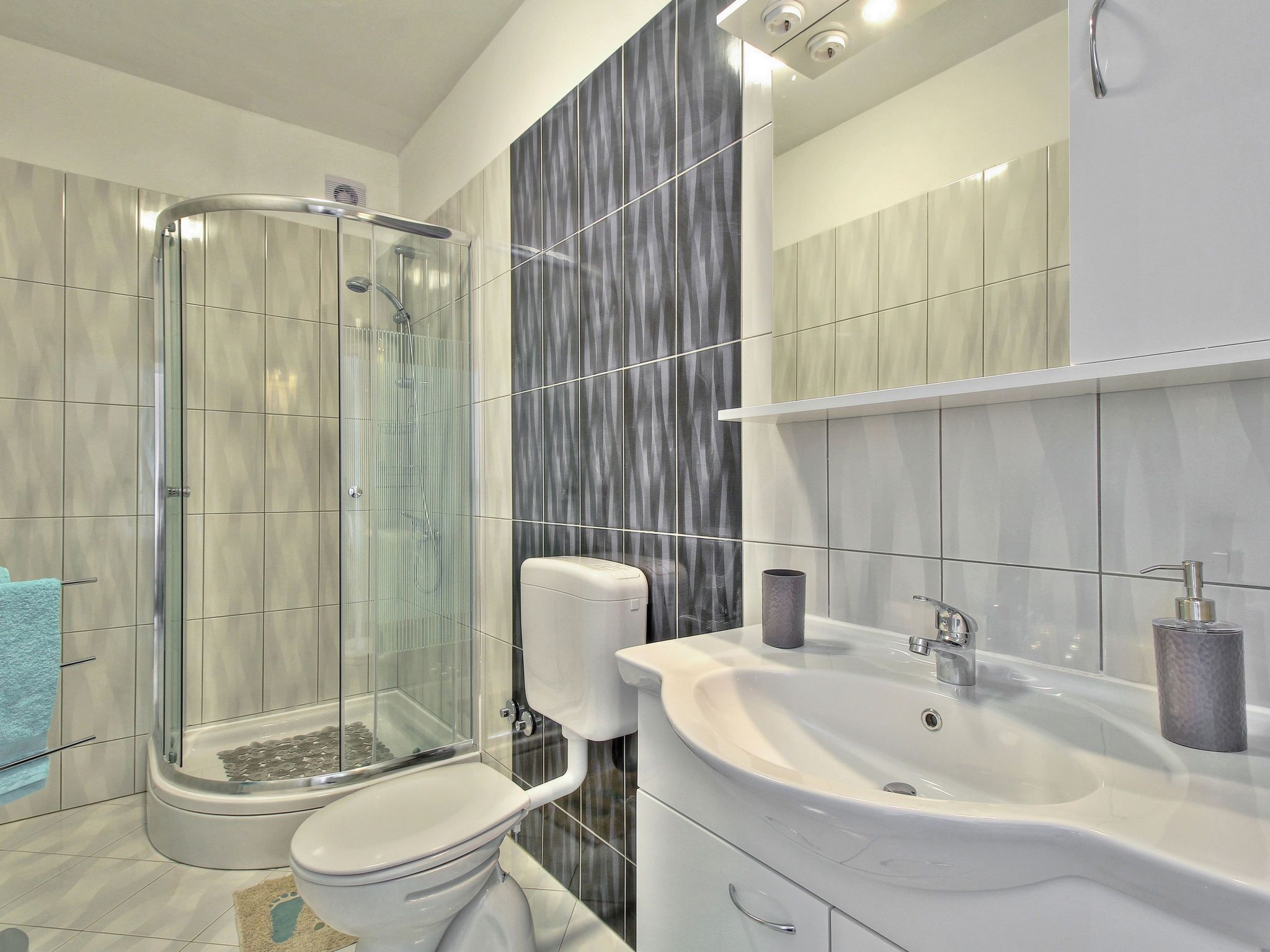 Une salle de bain moderne dotée d’une douche à parois de verre, de toilettes, d’un lavabo et d’un meuble-lavabo.