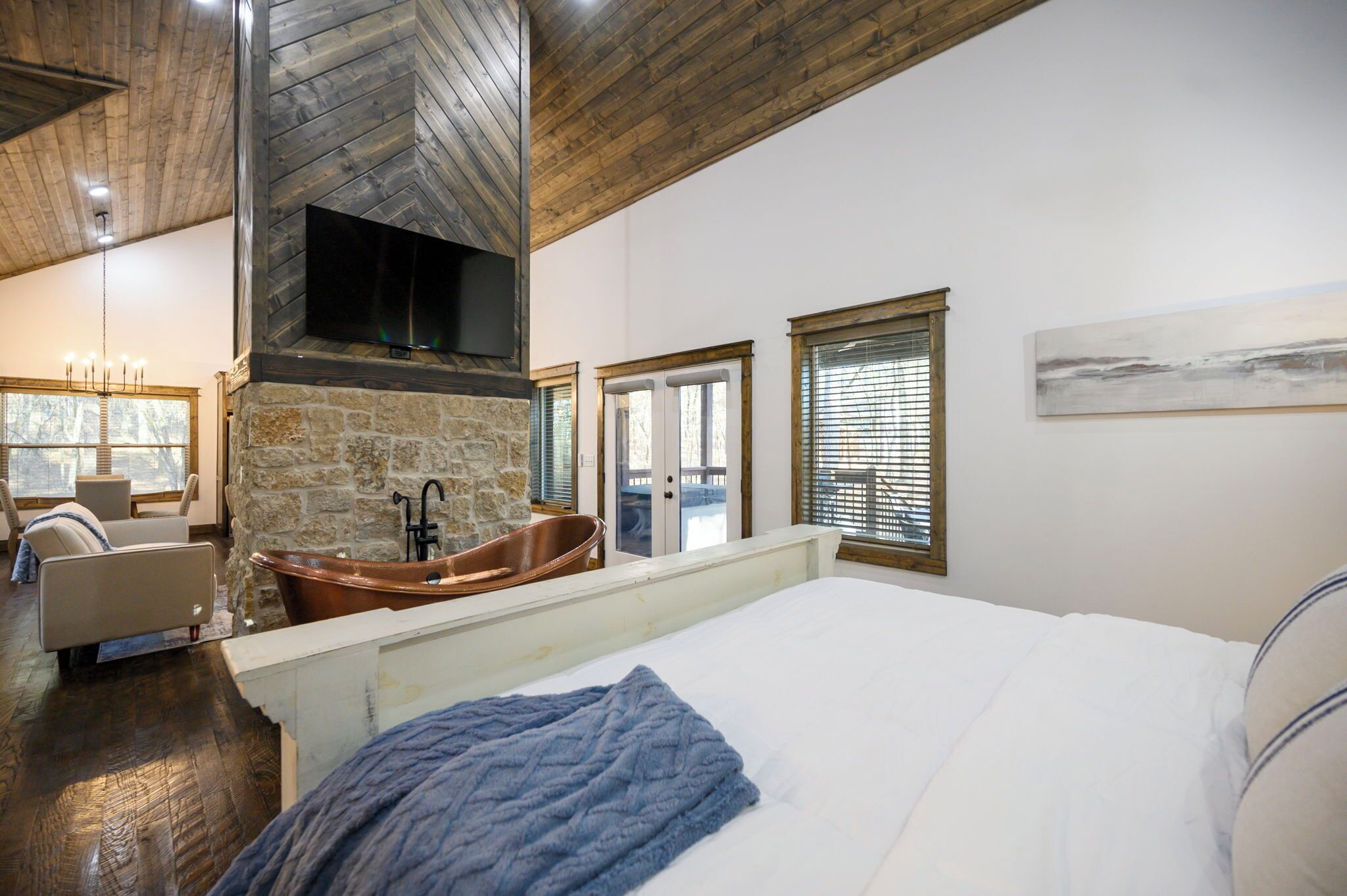 Ein Schlafzimmer mit einem großen Bett, einem Kamin aus Stein, einer Badewanne und Blick ins Freie.
