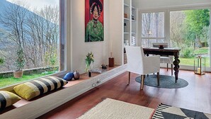 Un interior moderno con un gran ventanal, una zona de comedor y una estantería.