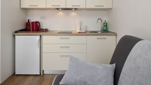 A compact kitchen with a refrigerator, a coffee maker, and a sink. - Apartments Ivo by Interhome (Polje)