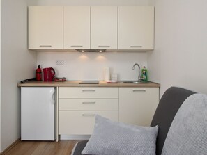 A compact kitchen with a refrigerator, a coffee maker, and a sink. - Apartments Ivo by Interhome (Polje)