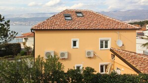 A building with a tiled roof, multiple windows, and air conditioning units. - Apartments Ivo by Interhome (Polje)