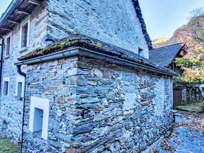 Un bâtiment en pierre doté d’un toit à forte pente, d’une petite fenêtre et d’une porte.
