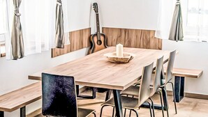Un coin repas avec une table en bois, des chaises, une guitare et un luminaire suspendu.
