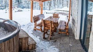 Un espace extérieur aménagé en bois, avec un jacuzzi, des bancs et une table.