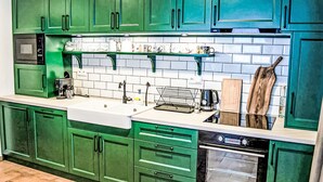 Une cuisine avec des meubles de couleur verte, un évier blanc, une cuisinière et un four à micro-ondes.