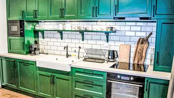 Une cuisine avec des meubles de couleur verte, un évier blanc, une cuisinière et un four à micro-ondes.