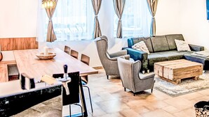 Un salon moderne avec une table à manger en bois, des canapés gris et une table basse.