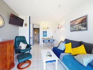 A living room with a sofa, armchair, coffee table, and a flat-screen TV mounted on the wall. - Le Saint Hilaire by Interhome (Talmont Saint Hilaire)