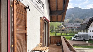 A balcony with wooden furniture, a view of a residential area, and a sign for 'PERMARKT BÄCKEREI CAFE'. - Sommer Apartements Schwarzwald by Interhome (Simonswald)