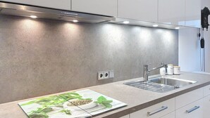 A modern kitchen with a stainless steel range hood, two sinks, and a countertop with a decorative mat. - Sommer Apartements Schwarzwald by Interhome (Simonswald)