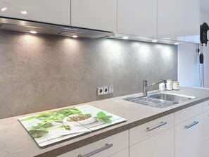 A modern kitchen with a stainless steel range hood, two sinks, and a countertop with a decorative mat. - Sommer Apartements Schwarzwald by Interhome (Simonswald)