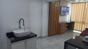 A modern bathroom with a white sink, wooden cabinets, and a tiled floor.
