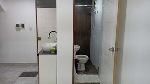 A compact bathroom with a sink, toilet, and shower.
