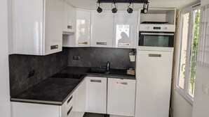 Eine kleine Küche mit weißen Schränken, einer schwarzen Arbeitsplatte und einem eingebauten Backofen.