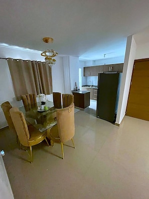A compact living space with a dining area, kitchenette, and a door leading to another room. - Luxury Hotel style Apartment. With a/c, hot and cold water. 3bs 2 bathroom  (Santo Domingo Este)