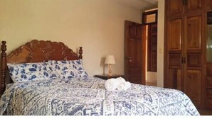 Un dormitorio con cama de madera, mesita de noche, lámpara y armario.
