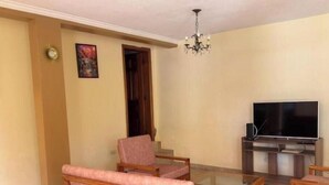 Una sala de estar con televisor, muebles de madera y una araña.