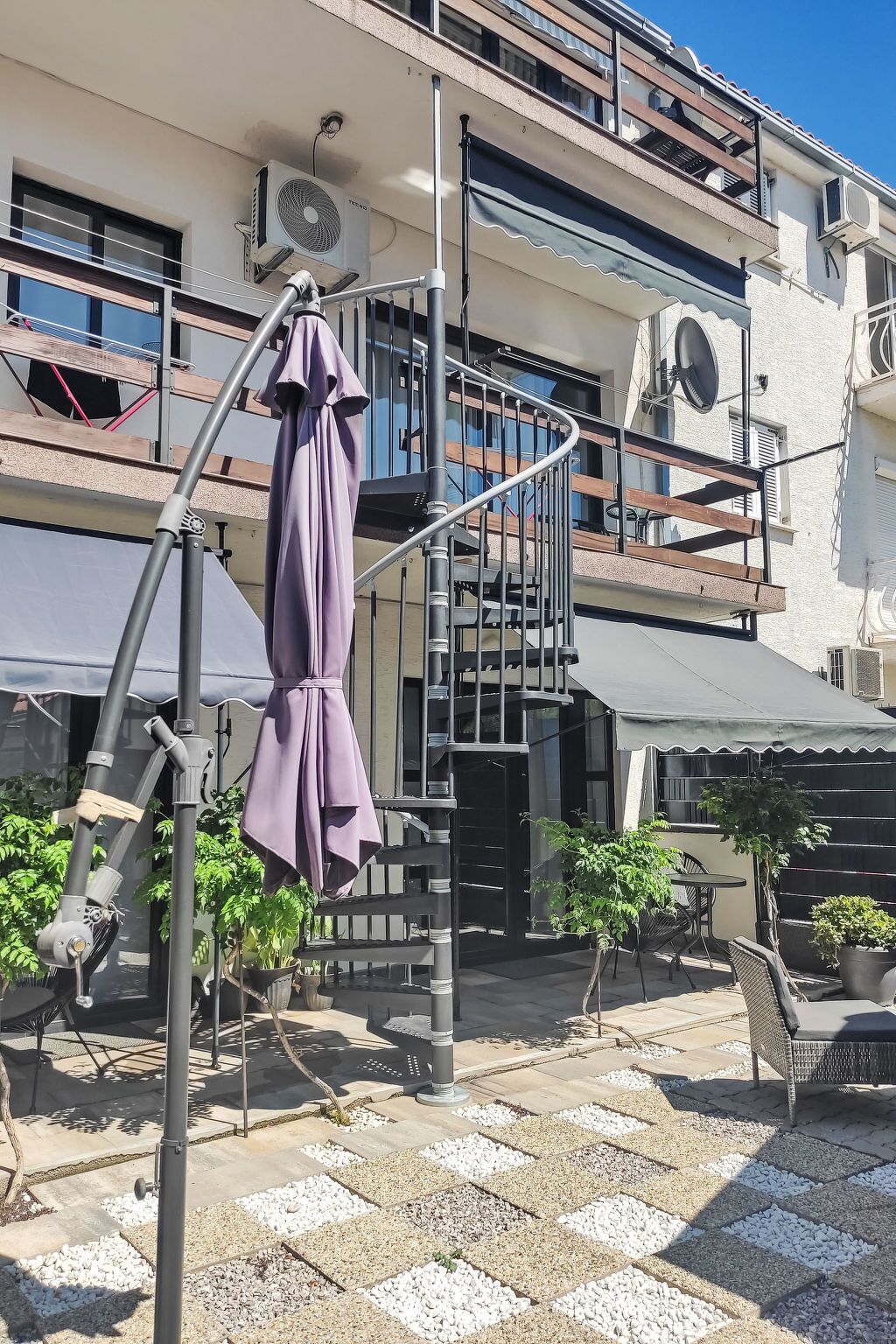 Un immeuble à plusieurs étages doté d’un espace extérieur avec des sièges, d’un escalier en colimaçon et d’un patio couvert.