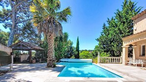 A swimming pool with lounge chairs, a pergola, and a stone wall. - La Sorba by Interhome (Saint Cyr sur mer Les Lecques)