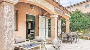 An outdoor patio with a dining table and chairs, a sofa, and a small table with a glass of water and a cup. - La Sorba by Interhome (Saint Cyr sur mer Les Lecques)