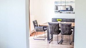 Un comedor con una mesa de madera, cuatro sillas, una lámpara colgante y un cuadro en la pared.