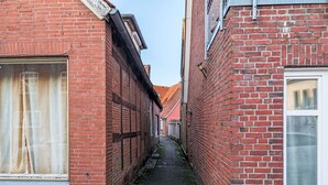 Un estrecho callejón entre edificios de ladrillo rojo con ventanas amplias y tejado de tejas.