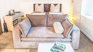 Un espacio habitable moderno y funcional con un sofá, almohadones, una revista y una mesita auxiliar.