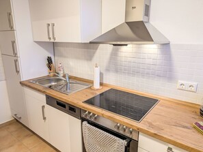 Een koelkast, een oven, een vaatwasser, kookgerei, borden en bestek
