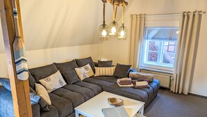 Ein modernes Wohnzimmer mit Ecksofa, weißem Couchtisch und einer Hängelampe.