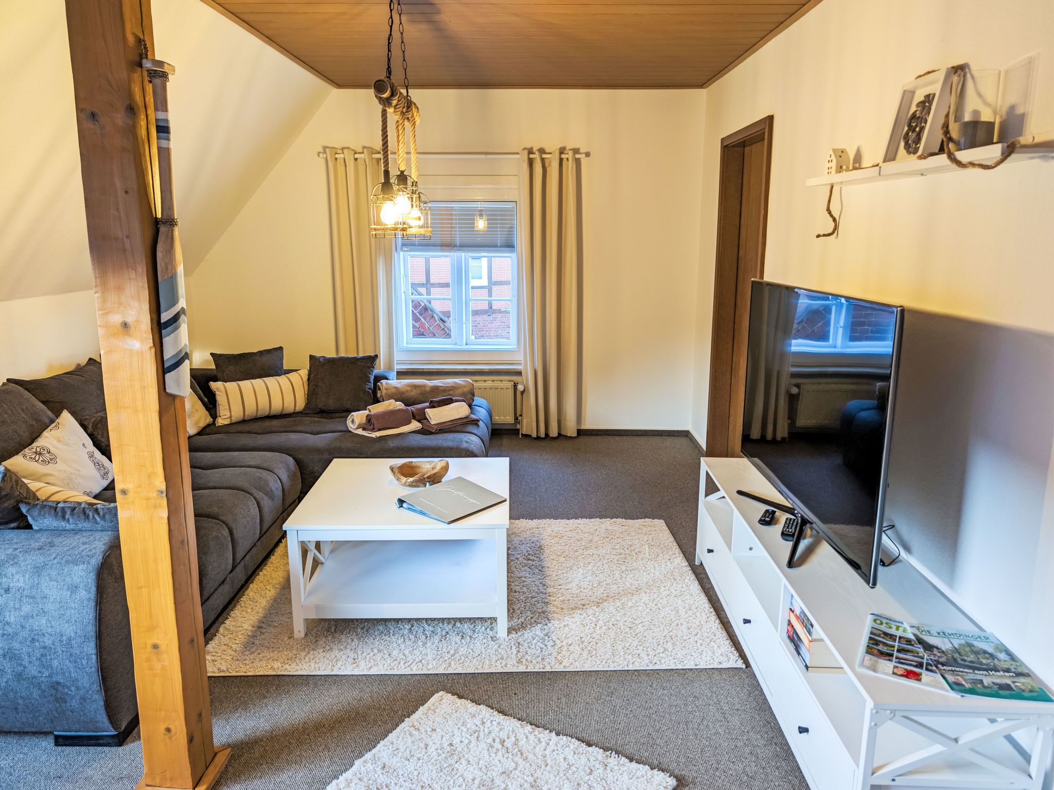 Ett mysigt vardagsrum med en soffa, ett soffbord, en tv och en bokhylla.