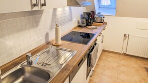 Eine Küche mit Spüle aus Edelstahl, eingebautem Backofen, Toaster und Fenster mit Blick auf Häuser.