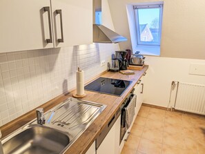 Eine Küche mit Spüle aus Edelstahl, eingebautem Backofen, Toaster und Fenster mit Blick auf Häuser.