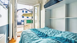 Un dormitorio con cama, ventana, puerta y vista al exterior.