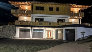 A two-story house with a garage, a balcony, and a well-lit entrance. - Josephine by Interhome (Auffach)