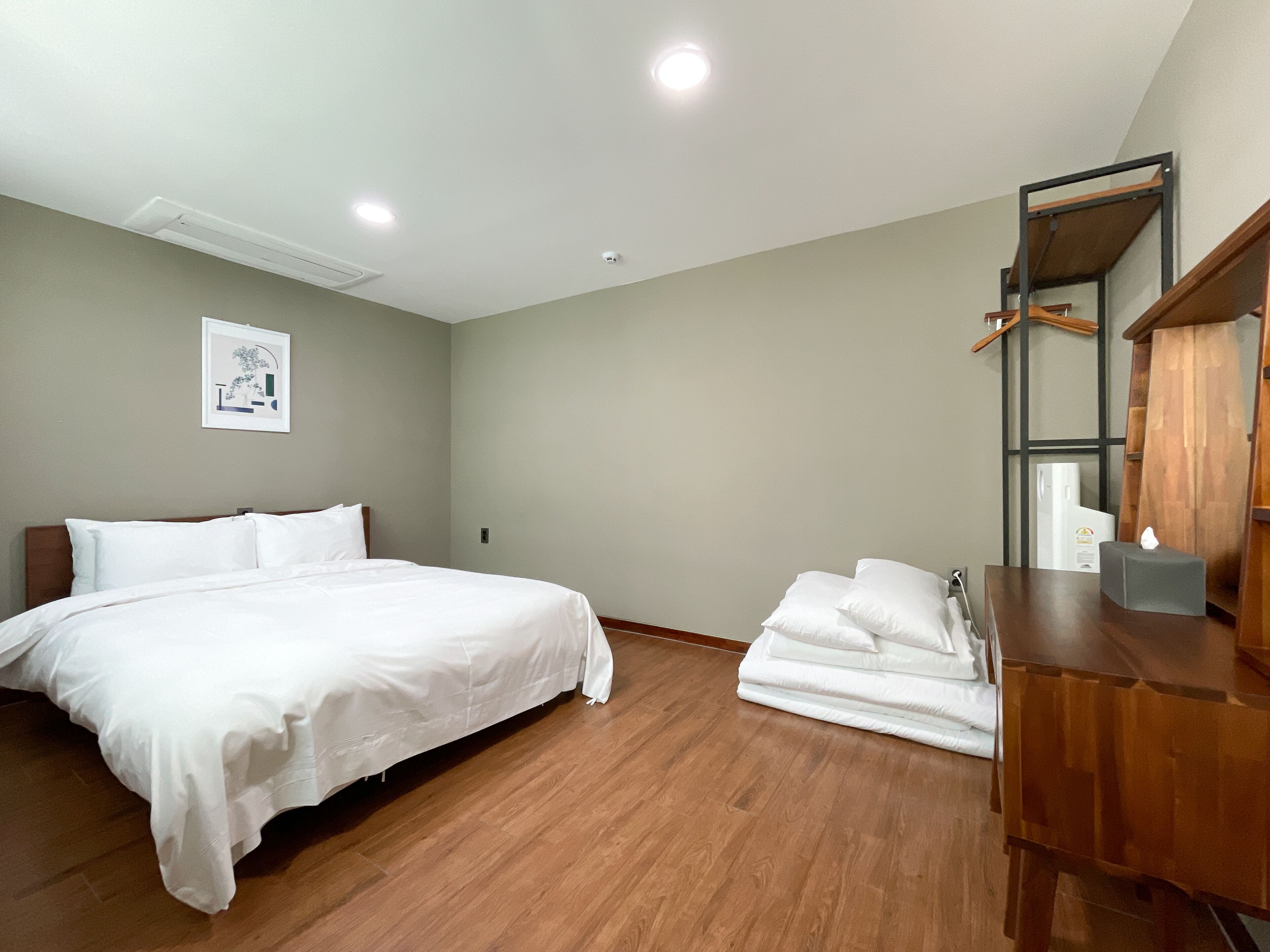 Una habitación de hotel con una cama, un tocador de madera, un espejo y un cuadro en la pared.