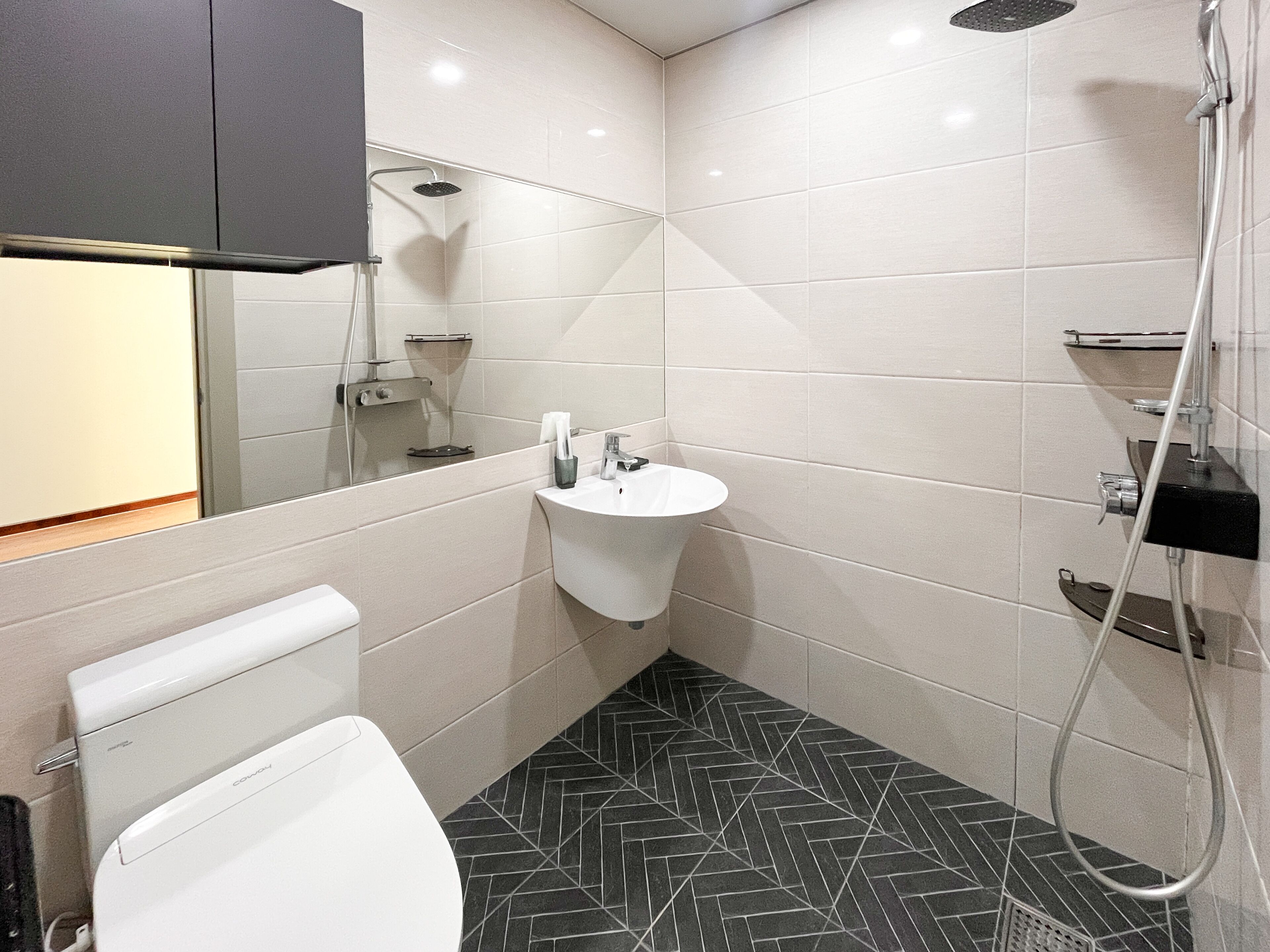 Ein modernes Badezimmer mit Toilette, Waschbecken, Dusche und gefliesten Wänden.