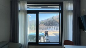 Una habitación con un ventanal grande, un sofá, una mesita y una silla.
