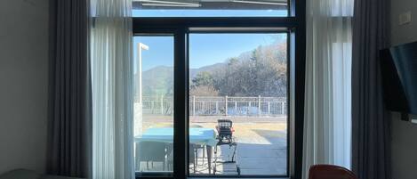 Una habitaciรณn con un ventanal grande, un sofรก, una mesita y una silla.