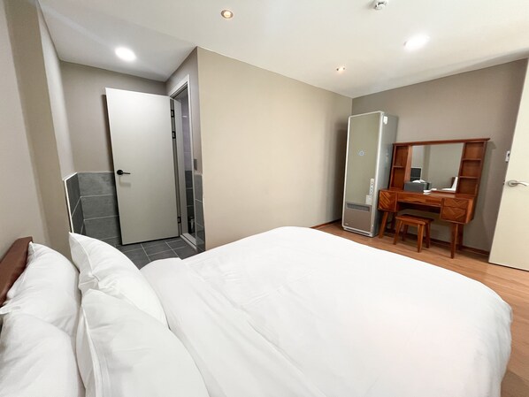 A hotel room with a bed, a desk with a mirror, a wardrobe, and a shower area. - OVER THE MOUNTAIN (Gapyeong)