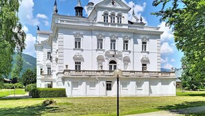 A large, white, classical-style building with symmetrical architecture, a central entrance, and a well-maintained lawn. - im Schlosspark mit Hallenbad by Interhome (Lofer)
